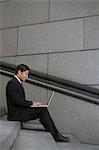 Businessman using laptop on city steps