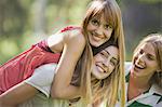 Young woman giving girlfriend piggyback ride