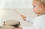 Baby boy playing drums, side view