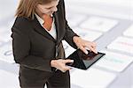 Businesswoman using digital tablet, close-up image of keyboard superimposed on background