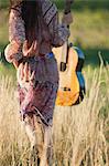 Frau Wandern durch Feld mit Gitarre, Rückansicht