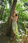 Young woman leaning against tree in woods