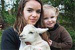 Teenage girl and little sister with pet lamb, portrait