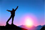 young man standing on the top of mountain and  watching the sunrise