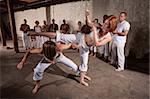 Capoeria martial artists performing techniques on concrete floor