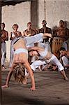 Pair of female capoeira practitioners performing with group