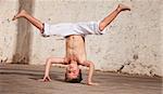 Young capoeria artist performing a headstand on concrete