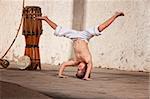 Cute capoeria boy in headstand with African music instruments