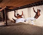 Two Brazilian martial artists performing techniques in mid-air