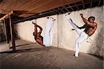 Handsome capoeria martial artists perform flying kicks
