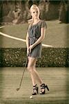 beautiful blonde girl in full lenght plays golf with blue short dress and hig shoes, vintage color shot