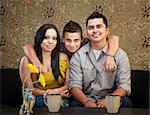 Young smiling Latino family sitting indoors together