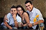 Happy Latino family of three embracing on a sofa