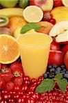 A glass of orange juice surrounded by fresh fruits