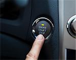 finger pressing the Engine start stop button of a car