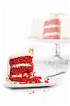 Scheibe Roter Samt-Kuchen auf einem Teller mit den ganzen Kuchen im Hintergrund