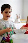 Young boy sifting flour into a bowl