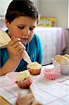 Young boy icing cupcakes