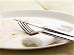 A dirty plate, cutlery and a paper napkin