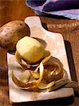 Potatoes, whole and peeled on a wooden board