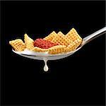 Corn Square Cereal with a Strawberry in a Spoon with Milk Dripping; Black Background