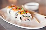 Spicy Tuna and Salmon Sushi Roll on a White Plate; Chopsticks