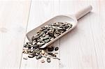 Sunflower seeds, pumpkin seeds and pine nuts on a wooden scoop