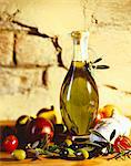 A carafe of olive oil with olives and tomatoes