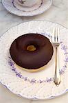 Ein Donut mit Schokolade glasiert und eine Gabel auf einem Teller