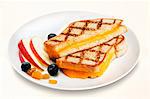 Halved Grill Cheese Sandwich on a White Plate with Fruit