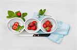 Fresh strawberries with leaves and flowers in bowls