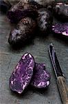 Vitelotte potatoes on a wooden board with a knife