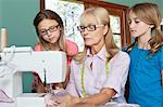 Granddaughters looking at grandmother sewing cloth