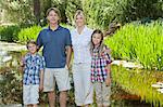 Family portrait of four standing against lake