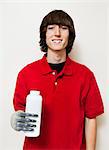 Portrait of a happy young man holding bottle with prosthetic hand over gray background