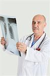 Porträt von schweren männlichen Oberarzt medizinische Röntgen über grauen Hintergrund halten
