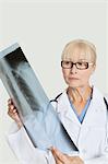 Senior female doctor examining x-ray over gray background