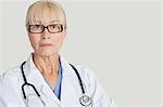 Portrait de sérieux femme médecin avec stéthoscope autour de cou sur fond gris