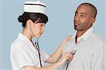 Female doctor listening the heartbeat of male patient over light blue background