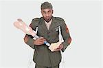 Portrait of disabled military officer holding prosthesis leg, studio shot on gray background