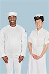 Portrait of happy female officer with male sailor, studio shot on light blue background