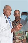 Ancien médecin avec soldat US Marine Corps, donnant au rapport des rayons x sur fond bleu clair