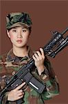 Portrait of young, female soldier with M4 assault rifle, Studio Shot on brown background