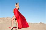 Full length of a young woman wrapped in red cloth on arid landscape