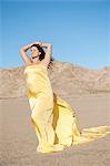 Young woman wrapped in yellow cloth on arid landscape