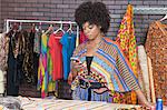 Attractive African American female fashion designer using cell phone