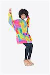 Full length portrait of happy African American woman in dashiki dancing over gray background