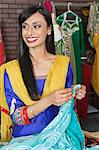 Indian female dressmaker looking away while holding sari