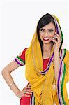 Portrait of an Indian woman in traditional wear answering phone call over white background
