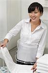 Weibliche Haushälterin Wegsehen, während die weißen Tuch Falten
